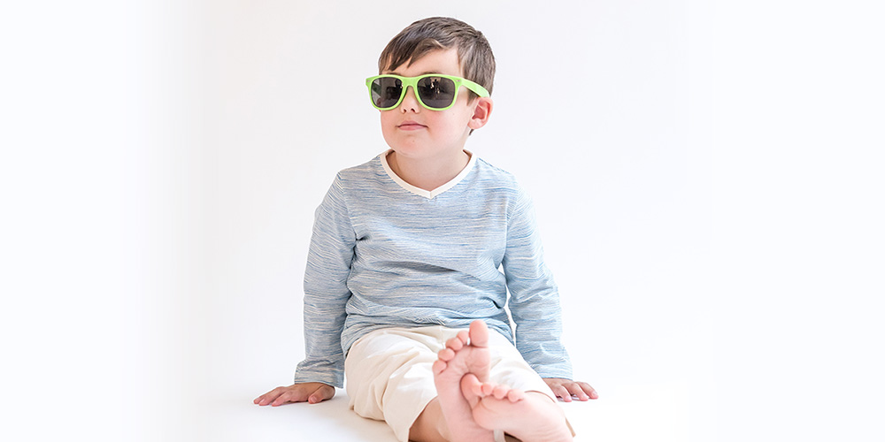 Kleiner Junge im blauen Pyjama mit Sonnenbrille