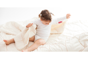 A young child looking at their duvet.