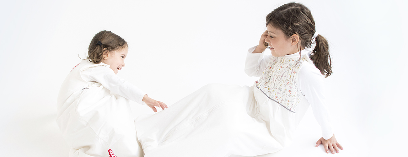 Two girls wearing breathable baby sleeping bags made from organic cotton and Swisswool
